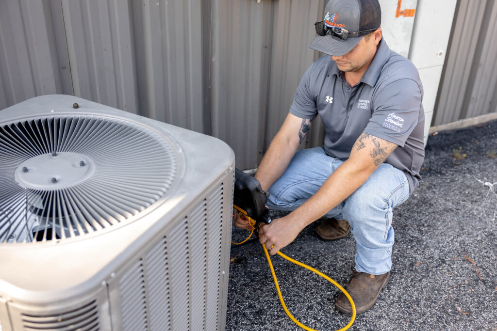 Emergency AC repair technician servicing outdoor condenser unit in The Woodlands TX