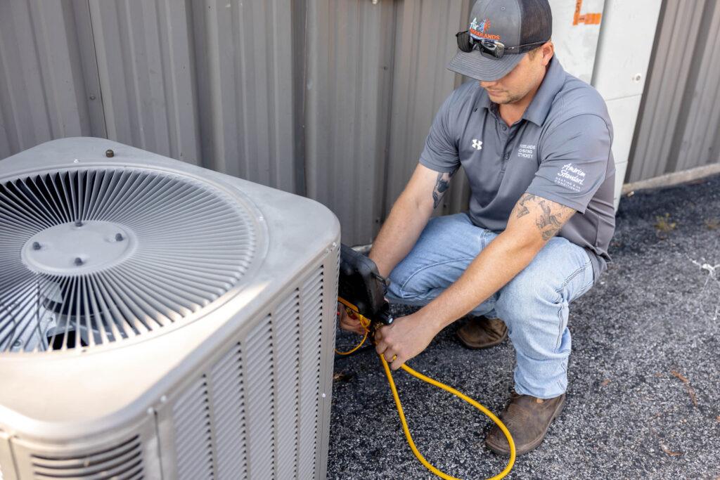 Emergency AC repair technician servicing outdoor condenser unit in The Woodlands TX