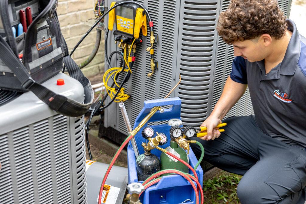 Air Woodlands certified HVAC technician using refrigerant gauges to service a residential air conditioning system in The Woodlands, Texas
